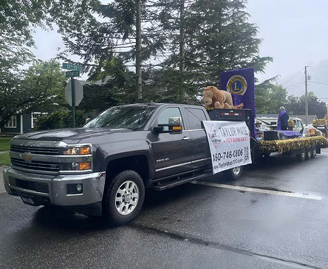 Supporting the community - Taylor Made Truck Driving School A gray Chevrolet pickup truck pulling a colorful float. The float had decorations and a big sign that said "Lions Club." There was another sign on the side of the truck with phone numbers and information. On the float, there was a big mascot that looked like a lion. - Taylor Made Truck Driving School